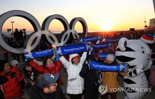 资料图片：1月1日，在江陵镜浦海边，平昌冬奥会志愿者们在宣传冬奥。（图片来源：韩联社）