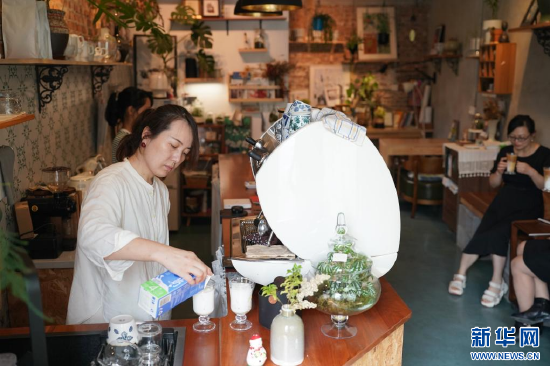 7月11日,“瓶子花”咖啡民宿主理人王妮娜(左)在为顾客制作饮品。新华社记者邵瑞 摄