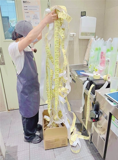 茶饮店新品受顾客喜爱 店员向记者展示小票