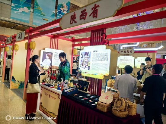 图为游客在在“锦绣经纬”工坊馨绣展位前欣赏手工刺绣挂件、刺绣配饰等文创产品。