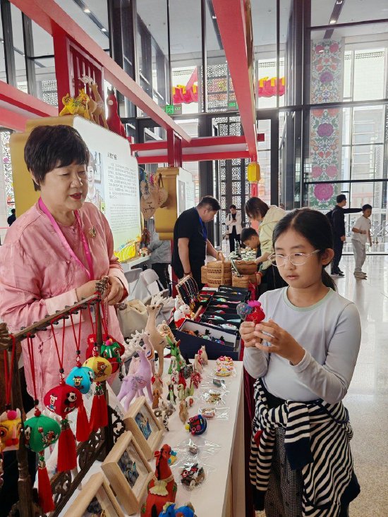 计清向小朋友介绍刺绣展品