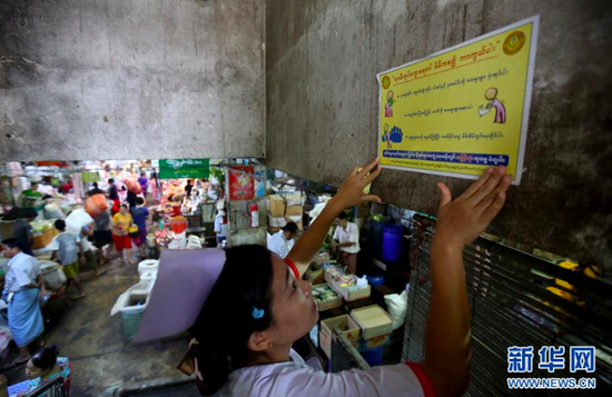 2019年8月8日，在缅甸仰光的一个市场，一名护士张贴预防甲型H1N1流感宣传单。图片来源：新华网
