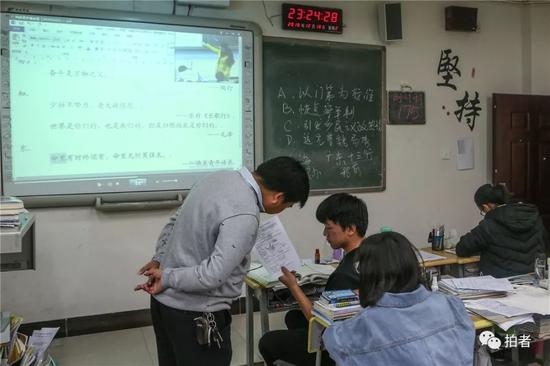 △ 培优班的耿添寿拿着试卷向地理先生挑问。