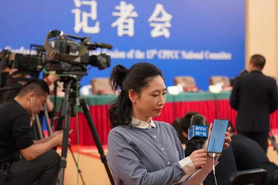 ↑3月10日，新华社记者在政协记者会开始前调试5G手机。新华社记者 何强 摄