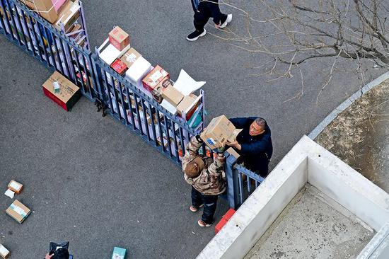 3月2日，北京一小区门口，人们隔着栅栏交接快递件。图/人民视觉