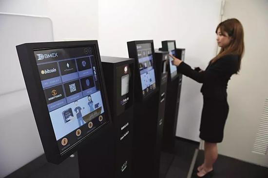 日本比特币交易所Bitpoint的职员演示虚拟货币ATM机的操作。图/视觉中国