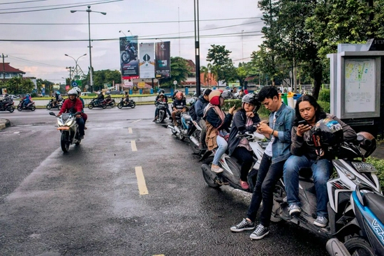 印度尼西亚当地年轻人在街边玩手机（视觉中国供图）
