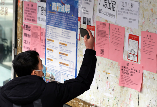 居民在拍摄招工广告 资料图 据视觉中国