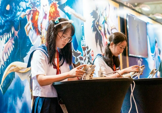 2017年的《王者荣耀》主题晚会上，两个女孩在玩游戏 （袁可佳 摄 视觉中国供图）