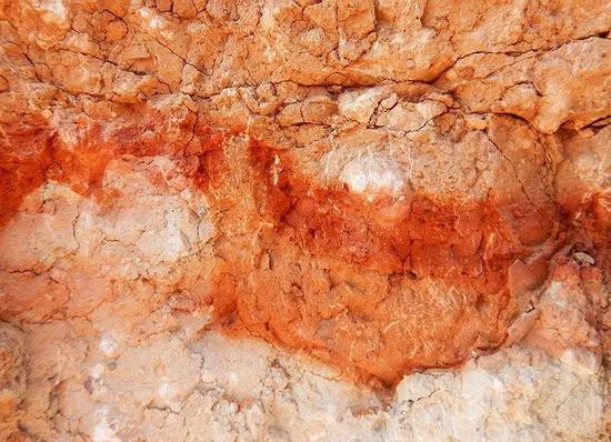 亮红色岩石层位于橘红色袋形层上方 ，袋形层中含有恐龙蛋化石碎片（袋形层左侧）。