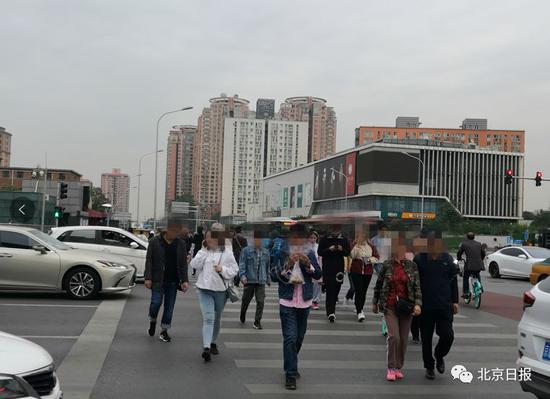 朝阳大悦城路口，不少行人过马路玩手机