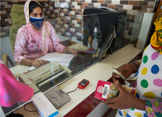 ■印度锡拉纳的业务员帮助一位女性完成一笔银行交易。