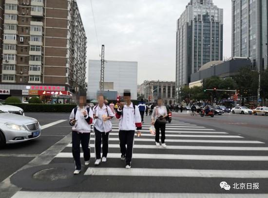 三名学生通过路口时玩手机