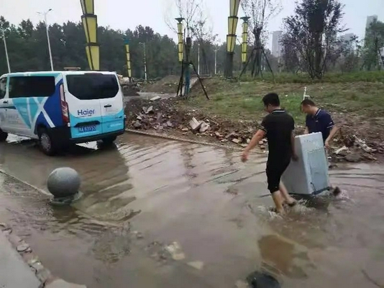 △7月22日，海尔售后服务人员在河南省焦作市武陟县詹店镇，冒雨为当地群众抢修家电。