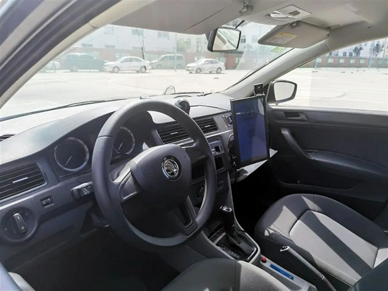 △图为提供智能教学的教练车，车上副驾驶位置前方有一块竖着的液晶屏。