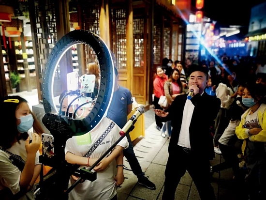 2020年4月26日晚，江西抚州市文昌里老街，一群年轻人在街边直播K歌。图/视觉中国