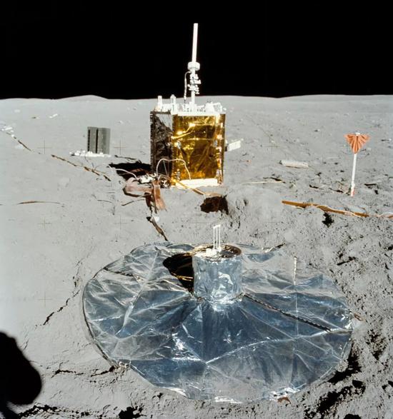 航天员在舱外活动中展开的月面试验装置。前景中间是被动地震试验仪，背景中间是“阿波罗月面实验装置”，左边是放射性同位素热电发电机，右边像旗子一样固定在地面的是主动地震试验仪
