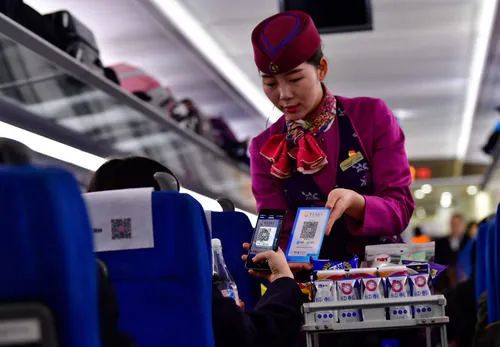 图为在重庆客运段G8516次列车上，一名旅客在使用手机扫码支付购买饮用水。新华社记者 刘潺 摄