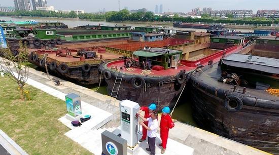 （图为京杭大运河湖州段服务区的船主使用岸电。）