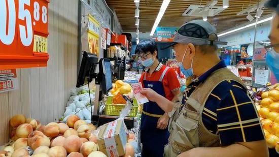 图为北京一菜市场内，多数老人仍习惯用现金购物。王毅卉 摄