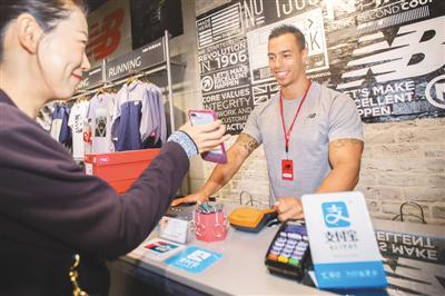 中国游客在澳大利亚悉尼的一家运动品牌店内通过手机支付方式购买商品。 　　许康平摄 (人民图片)