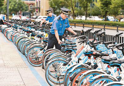 浙江省义乌市为规范共享单车停放等不断推出新举措，比如在城区施划停车泊位等。图为义乌市新科路附近一共享单车停车泊位，义乌市综合行政执法局稠江大队工作人员正在整理共享单车。吕 斌摄（人民视觉）