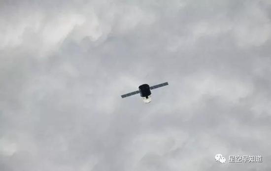 从空间站上看去，正在下方轨道上飞行的“龙”飞船，此时下方云层密布来源：NASA