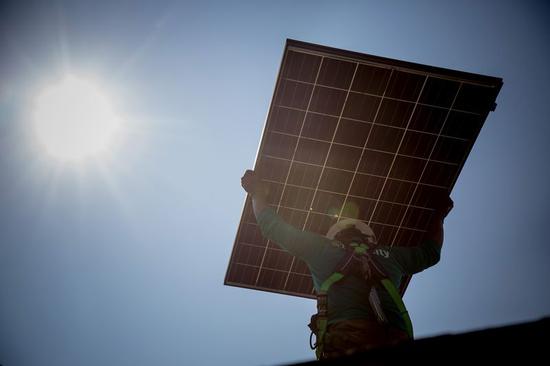 图7：SolarCity员工手举太阳能板