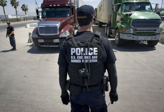 一名美国海关与边境保护局警官站在加利福尼亚州圣地亚哥Otay Mesa货运口岸的待检卡车前