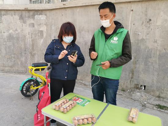 美团买菜地推员在社区周边拉新。