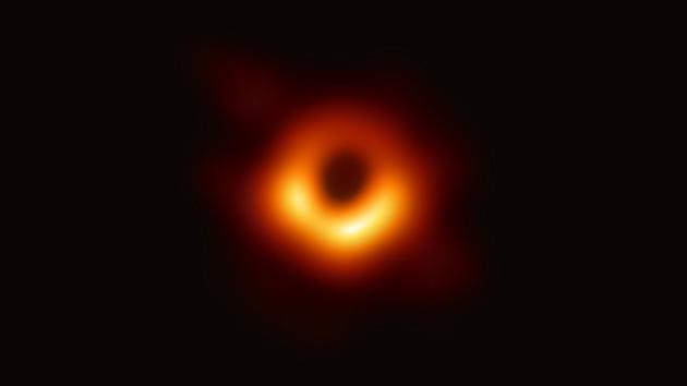 在这张由事件视界望远镜（EHT）合作项目拍摄的标志性图像中，超大质量黑洞在周围气体的辉光中投射出一个黑色的圆形“阴影”