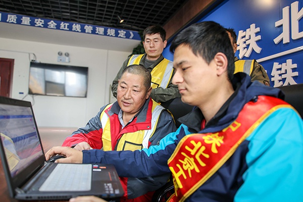 2019年12月12日,中铁北京工程局志愿者在商合杭铁路站房一标项目工地为农民工通过12306网站购买春运车票。 新华社记者 曹力 摄