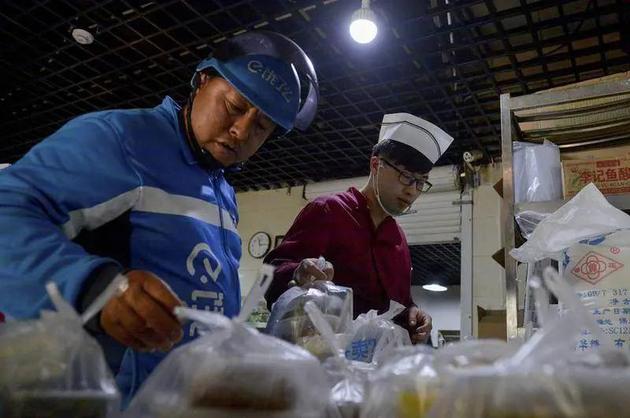 高峰期，骑手在一堆外卖中找餐。图源 / 视觉中国