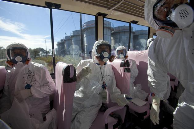 在这张2011年11月12日的资料照片中，东京电力公司的官员和日本记者乘坐公共汽车进入受损的福岛第一核电站