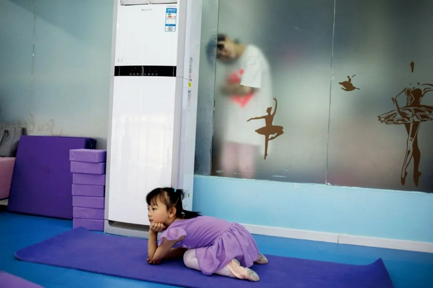 2018年5月26日，北京海淀区一家教育机构内，家长隔着玻璃墙观看教室内的舞蹈课。图/视觉中国
