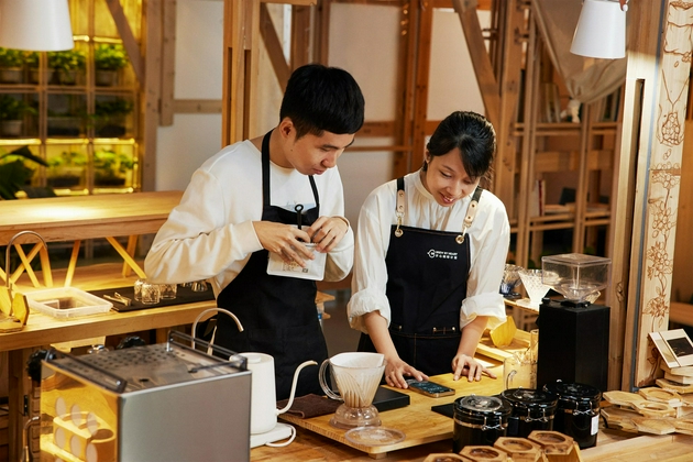 韦琳和她的学员泽宇使用 iPhone 的旁白功能读取蓝牙电子秤上的咖啡豆重量，继而制作一杯特调咖啡。