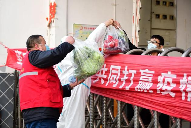 1月11日，石家庄某小区门口，志愿者给居民送蔬菜。/视觉中国