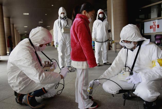 在这张2011年3月24日的资料照片中，即将被疏散的女童正在避难所接受辐射检查