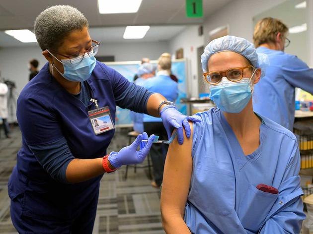 在美国弗吉尼亚州阿灵顿的弗吉尼亚州中心医院，一名注册护士正在为一名护士接种新冠肺炎疫苗