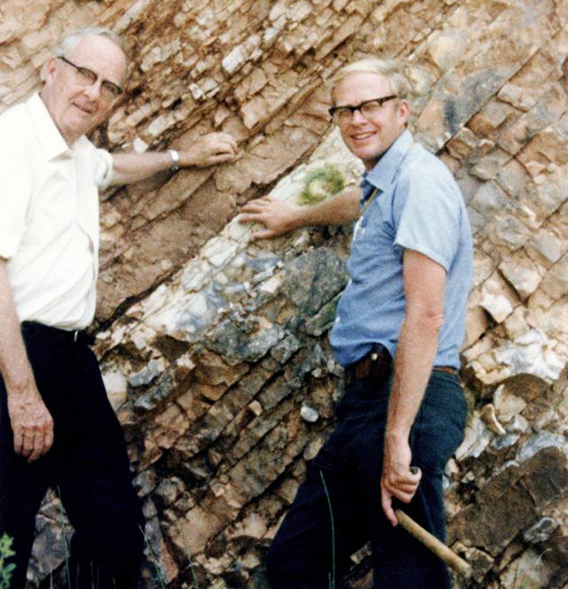 图中是沃尔特和父亲路易斯，他们俩站在意大利古比奥裸露岩层，他们用手触摸K-T边界的白垩纪石灰岩层。