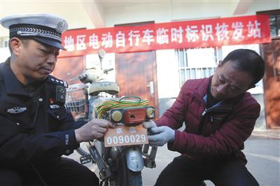 昨日，朝阳区垡头地区电动自行车临时标识核发站，民警帮市民安装临时标识。