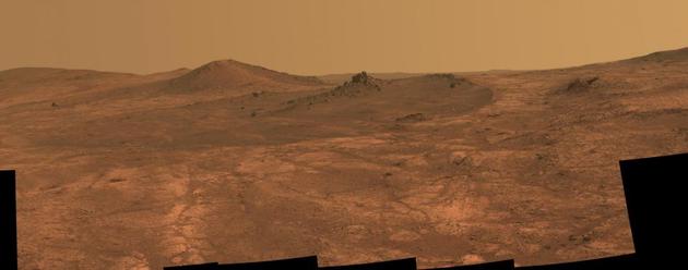 在这张由NASA火星探测器“机遇号”全景摄像机拍摄的照片中，一个名叫“圣路易斯精神”（Spirit of St。 Louis）的陨石坑和一块尖尖的岩石占据了画面的主体。