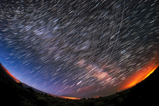 一群星链卫星（纵向平行曲线）经过美国新墨西哥州卡森国家森林公园附近上空。图片来源：M。 Lewinsky （CC BY 2.0）