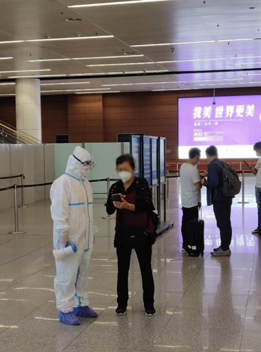 一位旅客正在向机场工作人员请教如何扫码登记。图/新浪科技