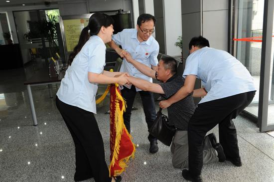 在一起故意杀人案宣判后,被害人家属送锦旗表示感谢,并突然下跪.