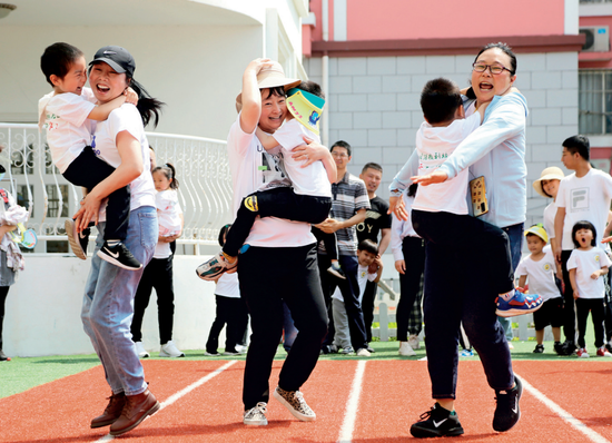 ▲ 5月30日，江苏省连云港市海州区一所幼儿园，家长与小朋友们一起进行亲子趣味游戏 王春摄 / 本刊