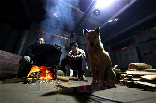 贾正标（右）和一条狗守在火塘边准备晚饭