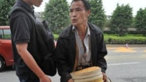 这名男子想把整桶玉米粒扛走，海都记者陈晋以身相挡，男子随后很不情愿地把玉米粒倒回路面，走了