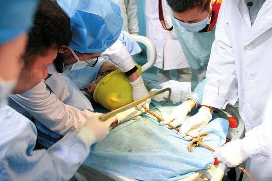 为顺利手术,消防官兵配合医务人员,用钢锯小心翼翼地锯切钢筋.