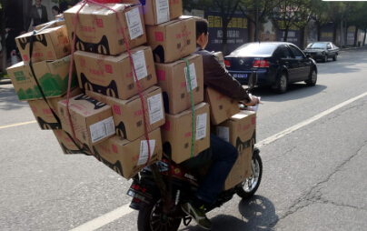 2014年11月13日,宁波马路上一快递员电动车满载天猫货物赶路. 资料图
